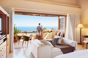 Couple standing on hotel balcony overlooking ocean